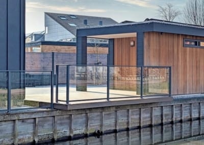 Glazen balustrade hekwerk overstekende vlonder bij water sloot kindveilig kindvriendelijk Glas met looppoort bootje | Consepto Hekwerk