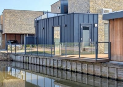 Glazen balustrade hekwerk op vlonder bij water sloot kindveilig kindvriendelijk Glas met looppoort bootje | Consepto Hekwerk