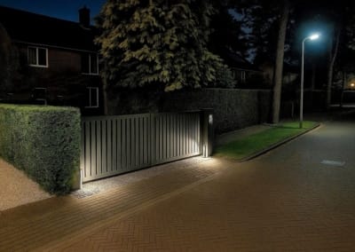 Impressies - Prefab elektrische schuifpoort rolpoort met haag in avond met verlichting | Consepto Hekwerk